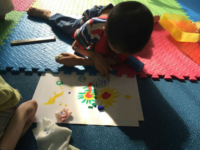 A child at the center enjoys finger painting.